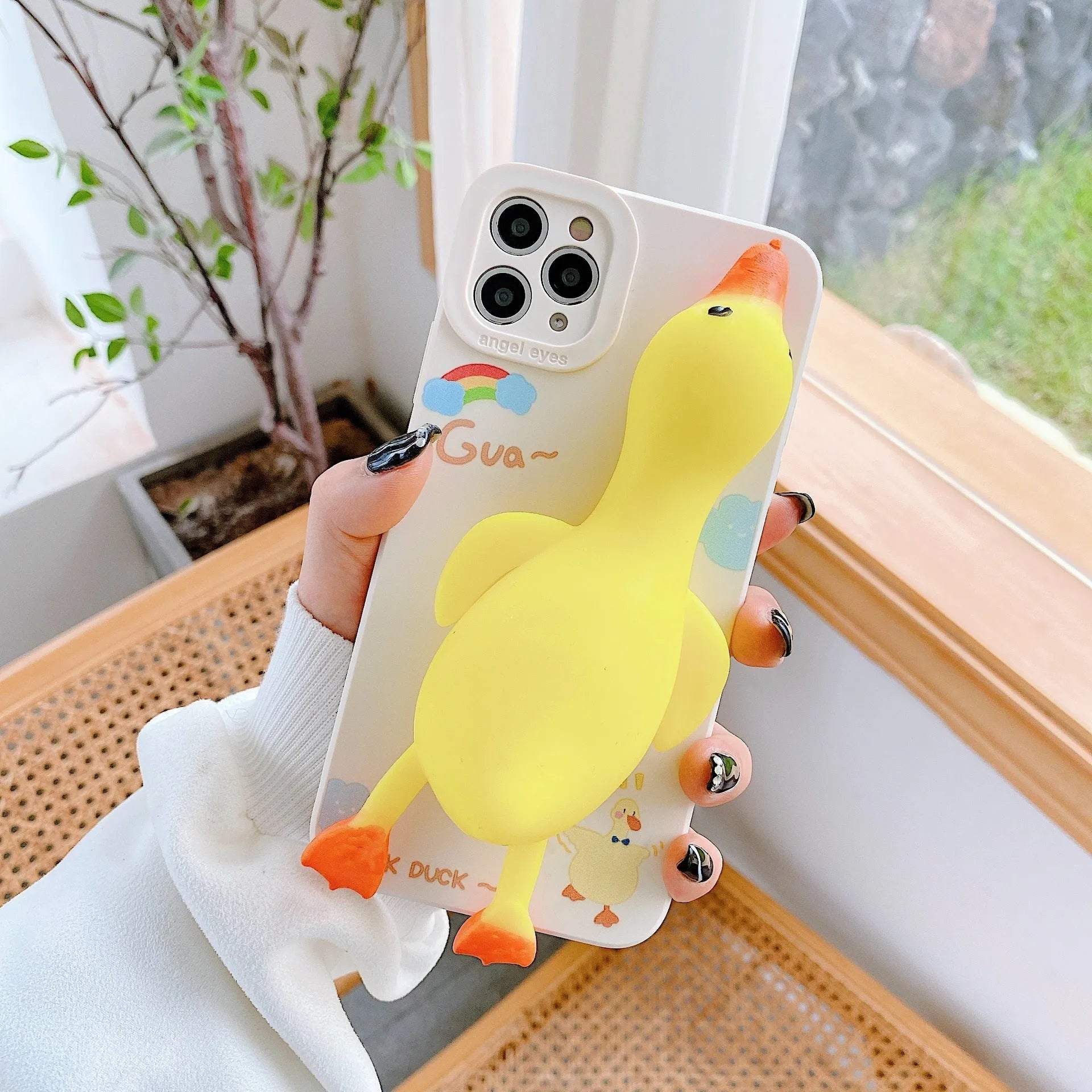 Cartoon print silicone phone case for iPhone in yellow, white, and pink colours.