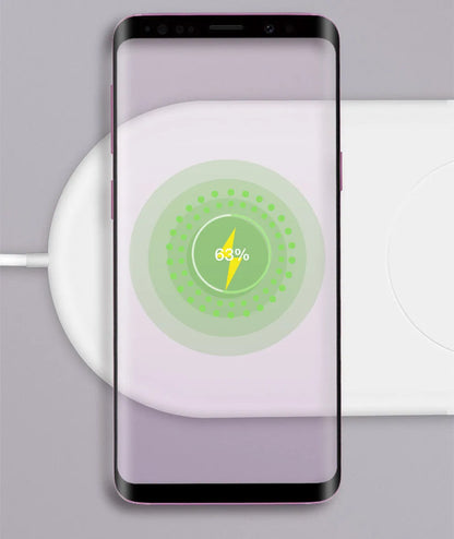 White dual wireless fast charging pad for two mobile phones on a wooden desk.
