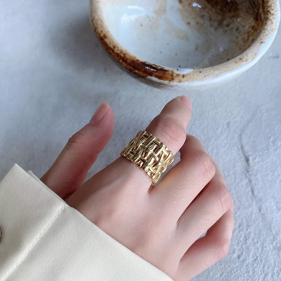 Woven brass ring with hollow cross design for women, available in gold and silver.