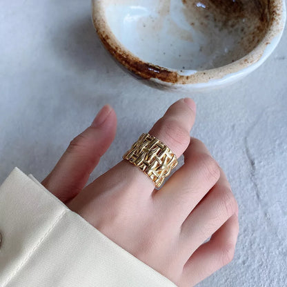 Woven brass ring with hollow cross design for women, available in gold and silver.