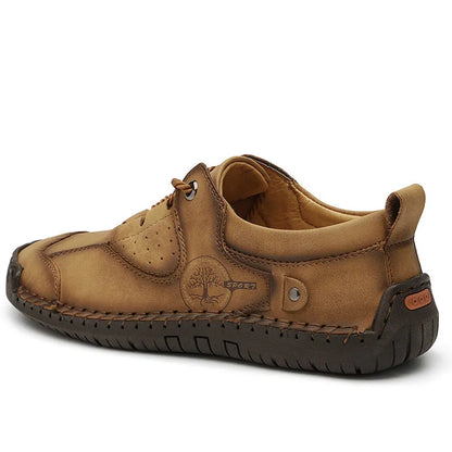 Men's plain black casual leather shoes with round toe and microfiber upper on a wooden floor.