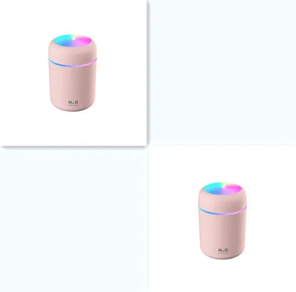 Pink car air purifying humidifier with LED lights on, next to a USB cable.