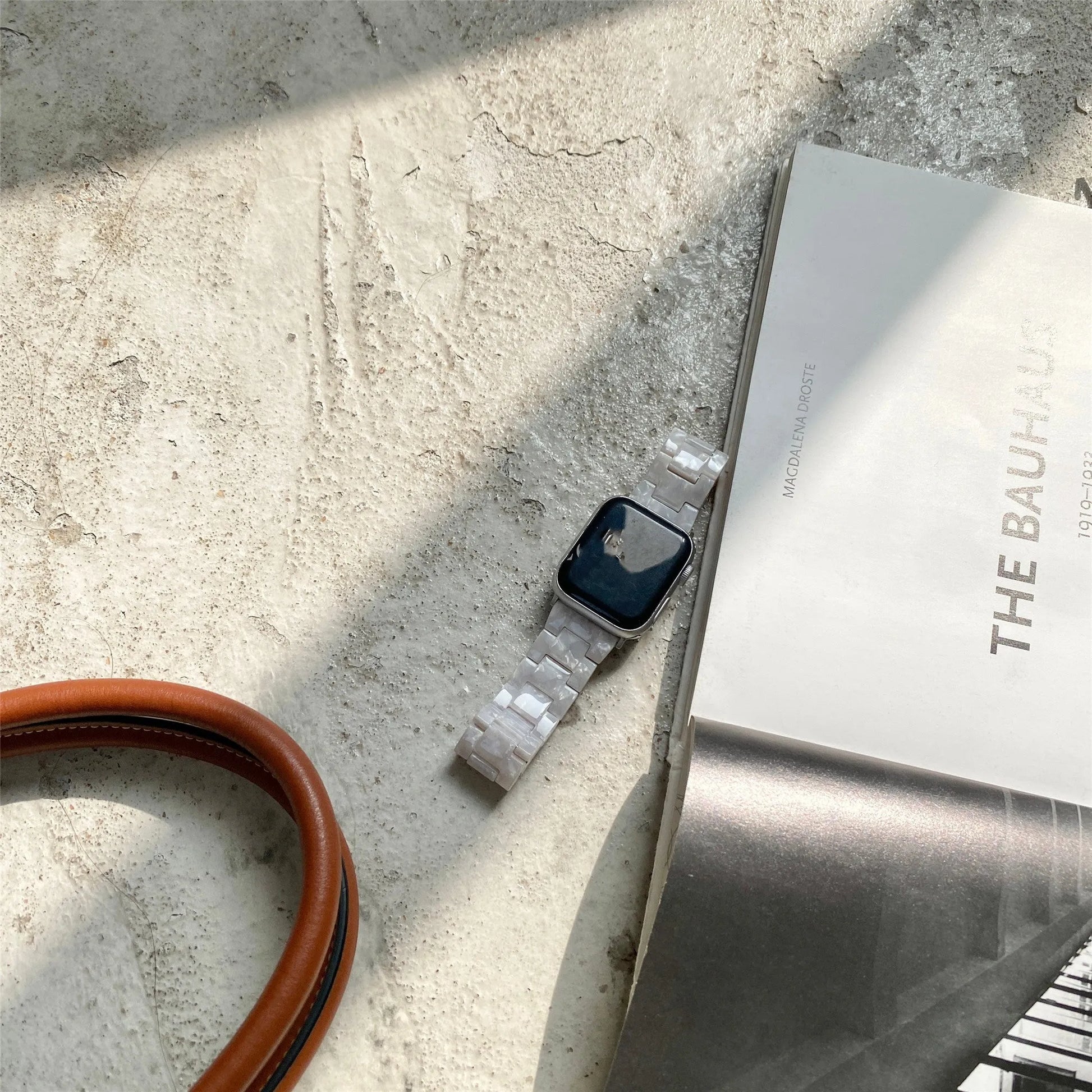 White and gray shell pattern resin strap for Apple Watch on a wrist.