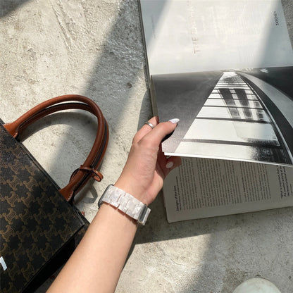 White and gray shell pattern resin strap for Apple Watch on a wrist.