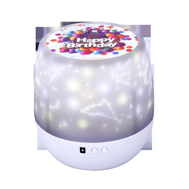 Compact white starry sky projector lamp with Bluetooth speaker projecting constellation images on a blue wall.