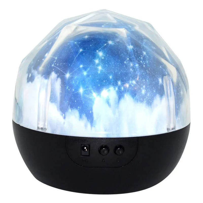 Compact white starry sky projector lamp with Bluetooth speaker projecting constellation images on a blue wall.