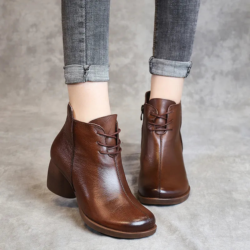 Women's brown leather retro Martin boots with a thick block heel and round toe on a wooden floor.