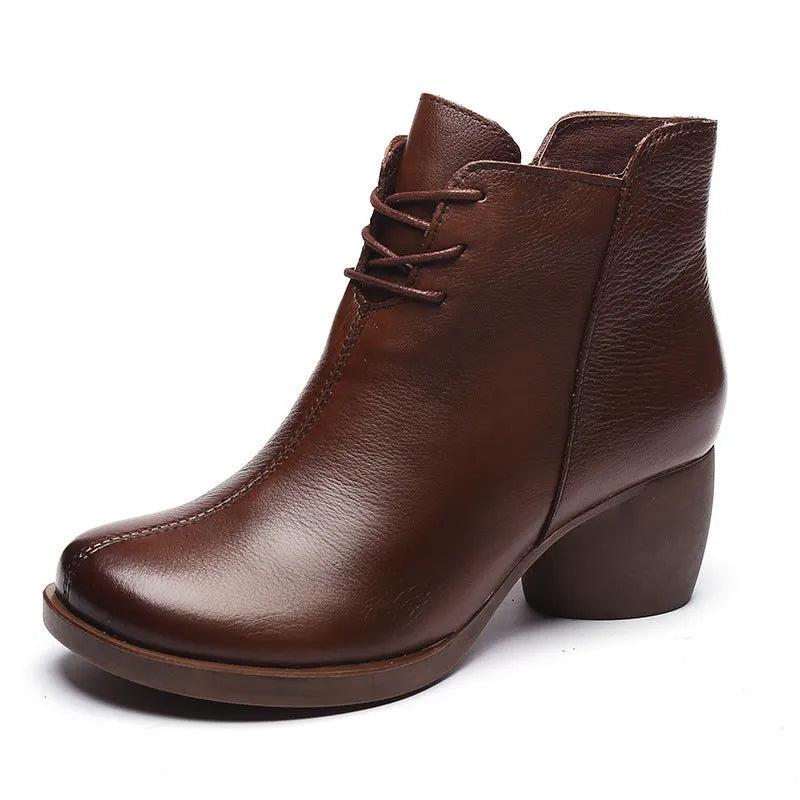 Women's brown leather retro Martin boots with a thick block heel and round toe on a wooden floor.