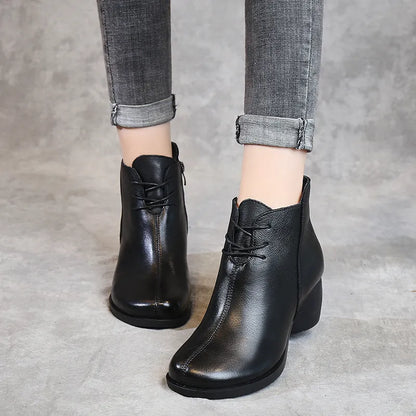 Women's brown leather retro Martin boots with a thick block heel and round toe on a wooden floor.