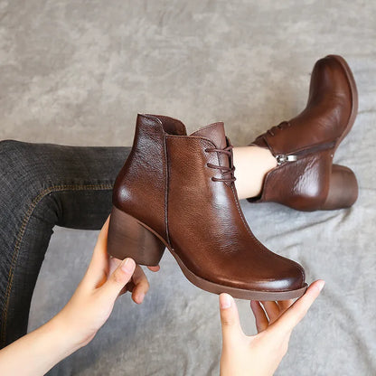 Women's brown leather retro Martin boots with a thick block heel and round toe on a wooden floor.
