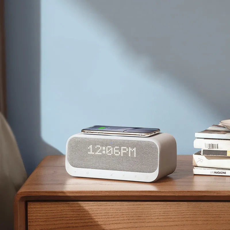 White Anker Soundcore all-in-one Bluetooth speaker with wireless charging pad and alarm clock display.