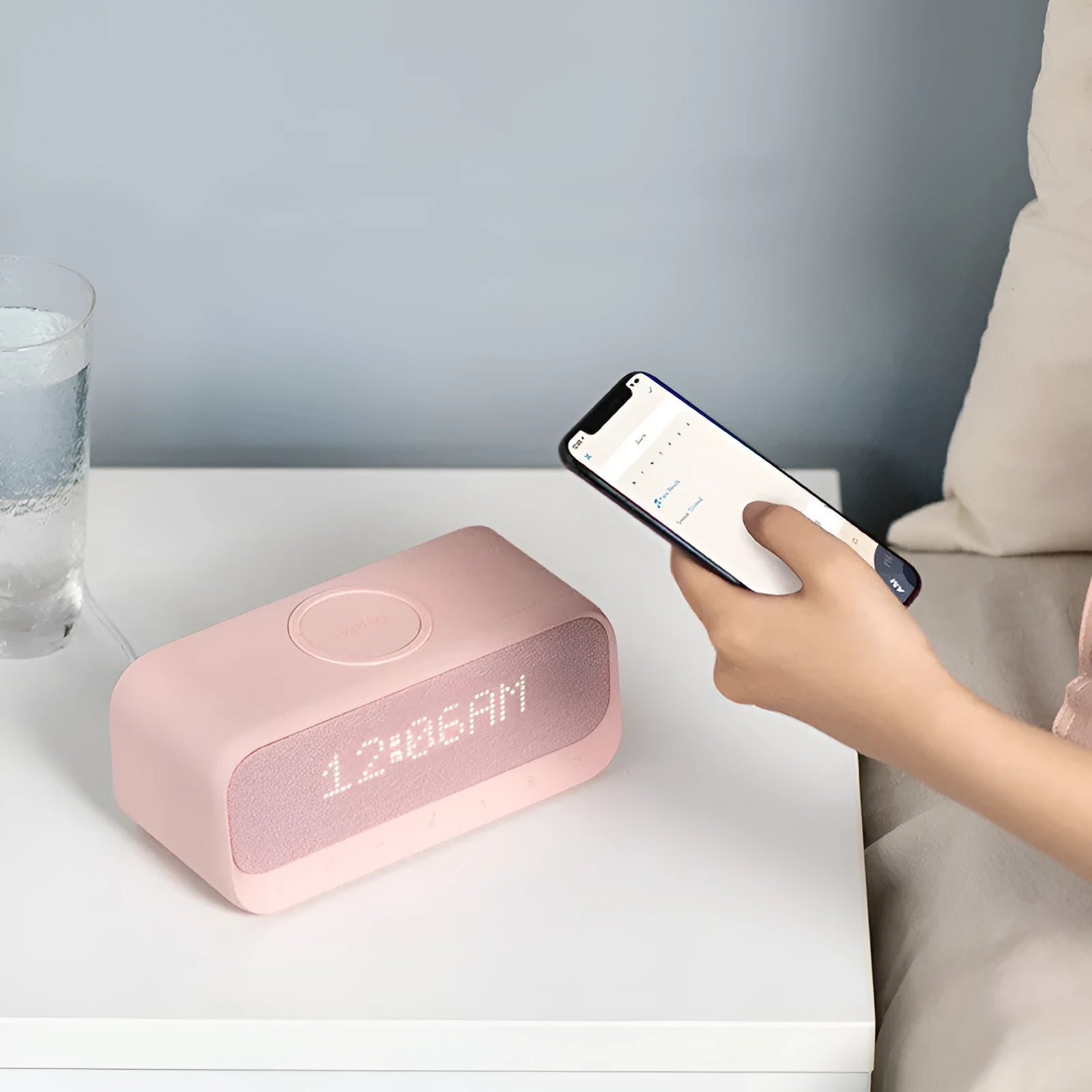 White Anker Soundcore all-in-one Bluetooth speaker with wireless charging pad and alarm clock display.