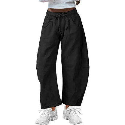 Loose grey cropped sweatpants with drawstring waist and side pockets on a casual model.