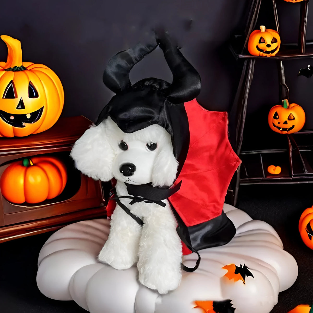 Small dog wearing a red bat devil cloak and pointed hat Halloween costume.