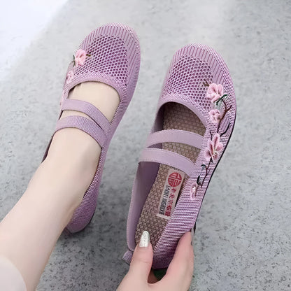 A pair of slip-on flat shoes with an elastic upper and rubber sole, shown in an embroidered colour option.
