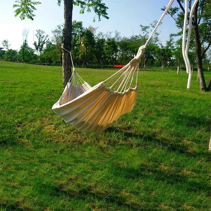 Cotton camping hammock with adjustable straps hanging between two trees in a forest