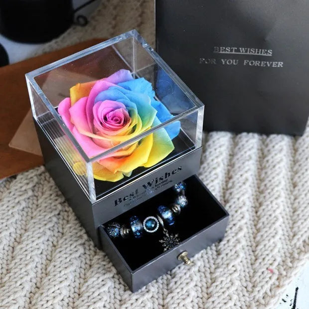 Blue and pink eternal flower gift box with roses and carnations on a table.