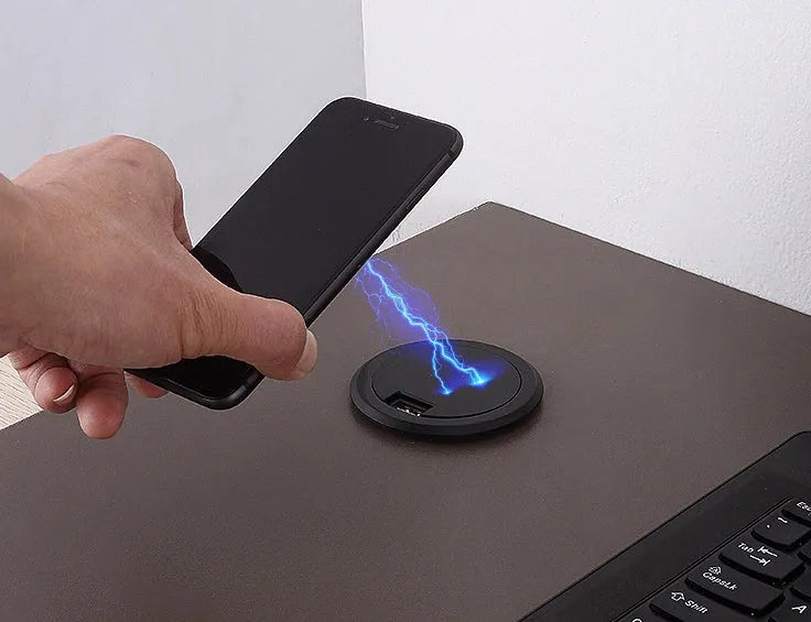 Round wireless charging unit for recessed installation in desks and tables, shown next to a smartphone.