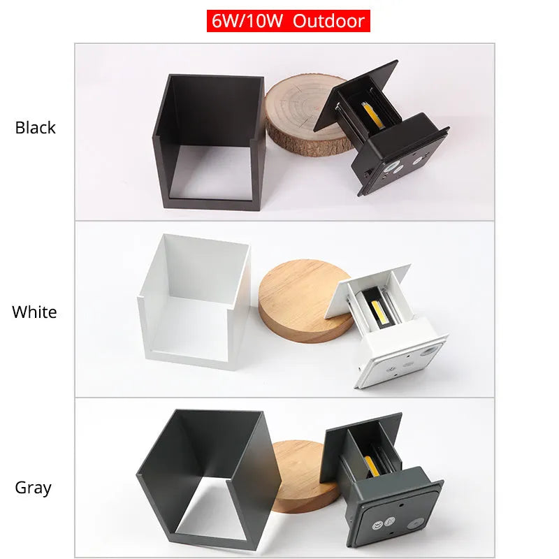 Compact cubic aluminium LED wall lamp in black mounted on a brick wall, emitting a soft glow.