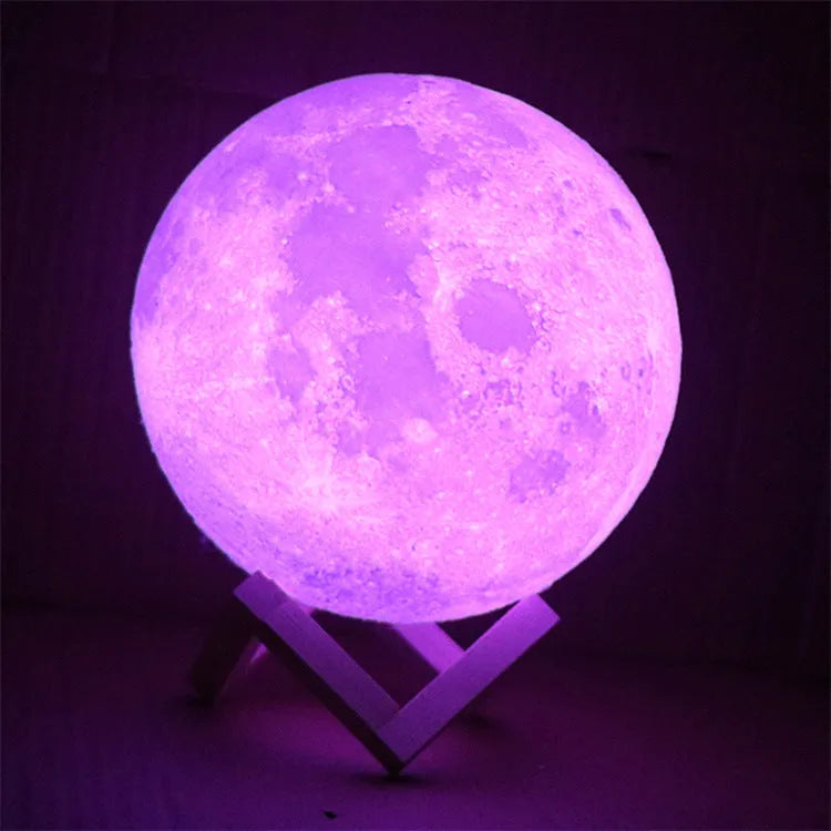 3D printed white moon lamp on wooden stand with textured lunar surface, glowing with warm yellow LED light.