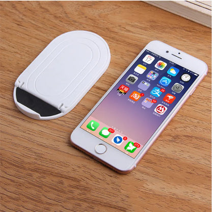 Black adjustable lazy bracket phone stand holding a mobile device at an angle on a wooden table.