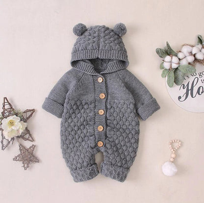 Baby wearing light blue knitted romper with hood and sleeveless design, single-breasted closure visible