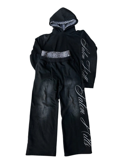Man wearing a black punk print hoodie and matching trousers, a casual lounge suit set.