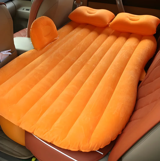 Black inflatable car bed with flocked surface and two pillows, shown folded into a chair inside a vehicle.