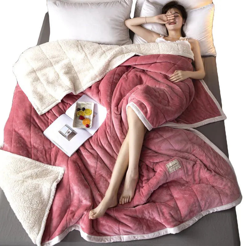 Thick pink coral fleece blanket folded on a twin bed.