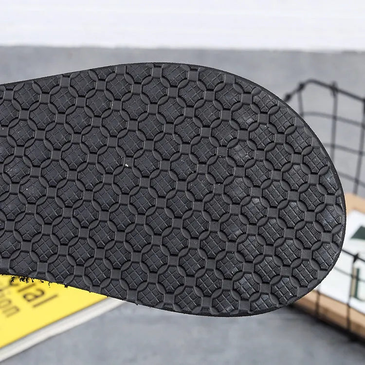 Women's brown bohemian slippers with a woven strap and a 5.5cm wedge rubber sole on a wooden deck.