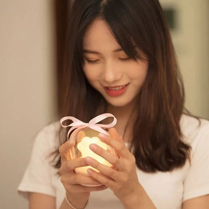 Grey cat paw shaped night light with USB port and button, glowing softly on a wooden desk.