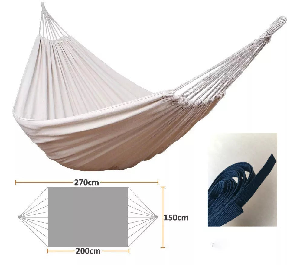 Cotton camping hammock with adjustable straps hanging between two trees in a forest