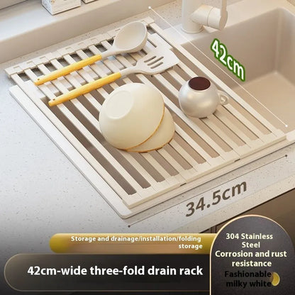 A milky white foldable stainless steel kitchen draining rack collapsed flat beside a kitchen sink.