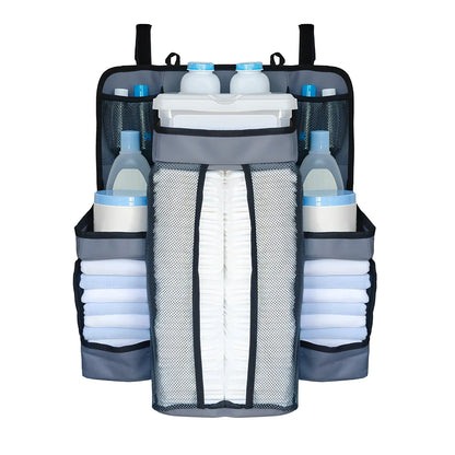 Grey baby nappy organiser attached to crib rail with Velcro straps, showing storage compartments for nappies and essentials