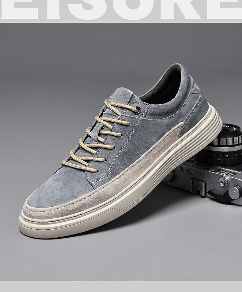 Men's grey low-top casual leather skate shoes with round toe and flat rubber sole on a wooden surface.