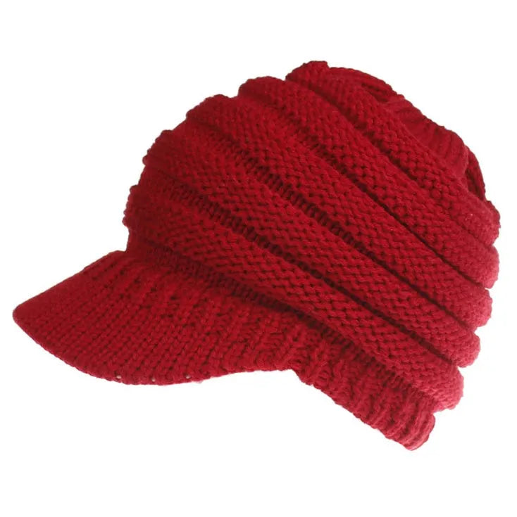 Woman wearing a light grey knitted ponytail beanie with her ponytail pulled through the hole in the back.