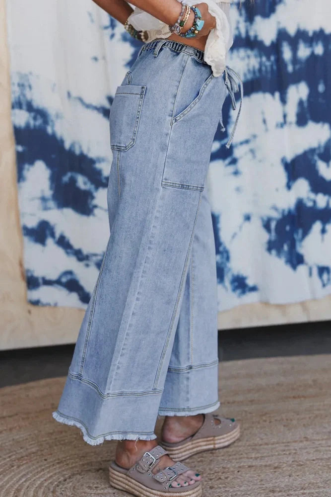 Beau Blue drawstring seam detail raw hem wide leg denim trousers with 75% cotton composition for breathability and 2% elastane for flexibility, offering a relaxed fit through wide leg design and adjustable waist with drawstring closure.
