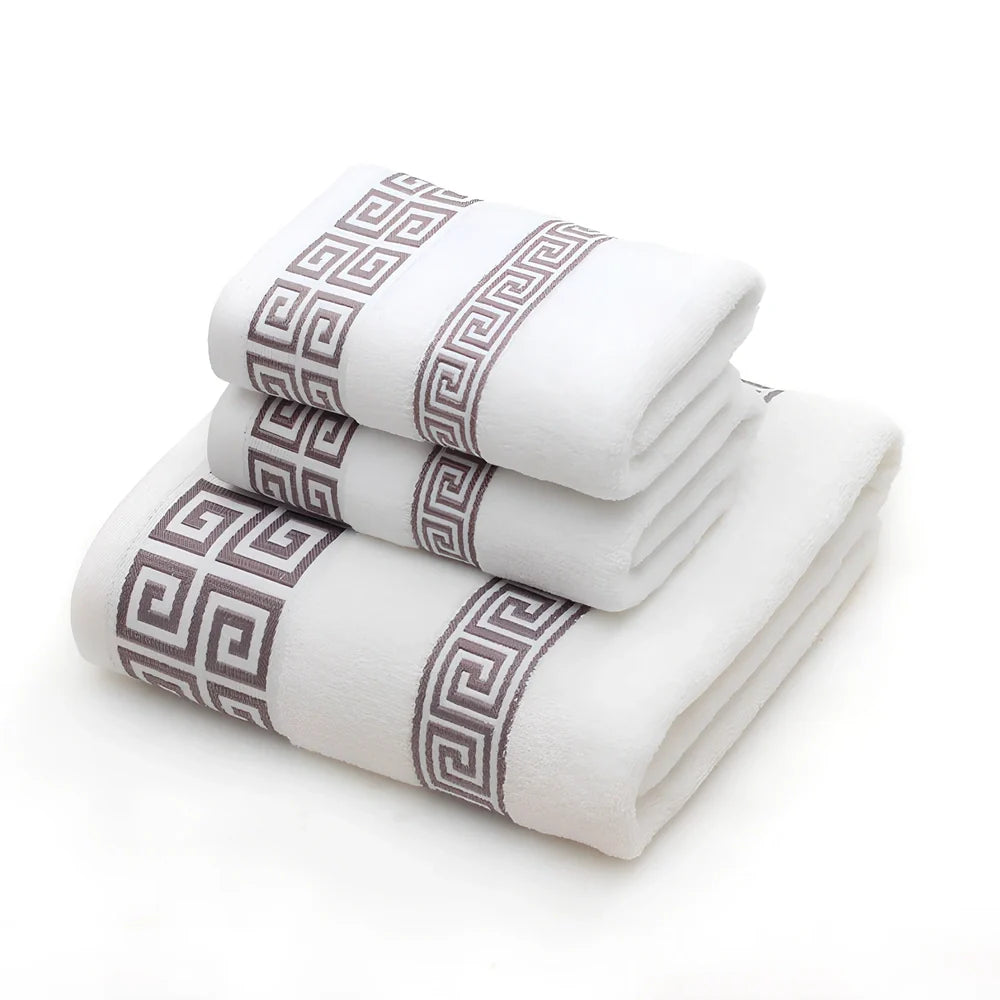 Three-piece cotton towel set showing 70cm bath towel and two 34cm hand towels in white, dark blue, and brown colours