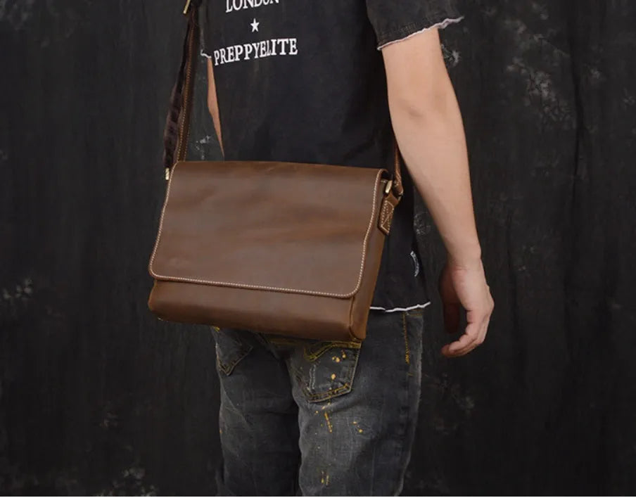 Vintage brown leather men's messenger bag with a cover flap, showing the internal document and phone pockets.