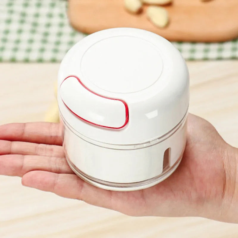 White manual food chopper with stainless steel blades on a kitchen countertop.