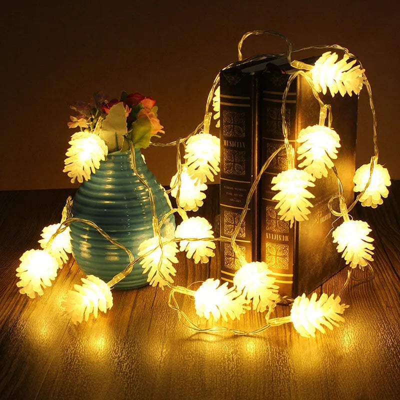 Warm white LED pine cone fairy light string on a green backdrop, showing plastic shell details.