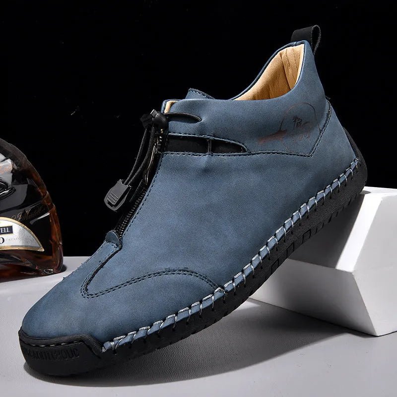 Men's black casual leather shoes with a mid heel, round toe, and visible stitching on a wooden floor.