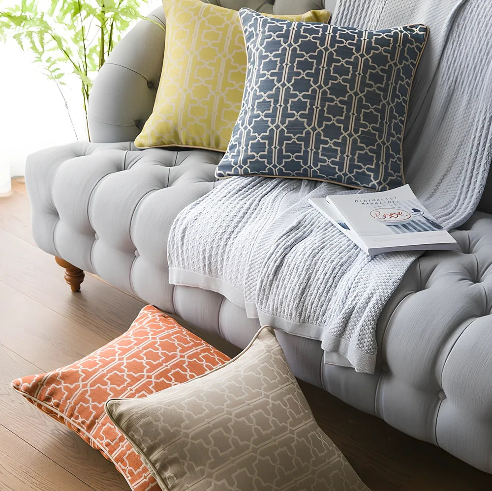 Square beige cushion cover with envelope closure on a grey sofa
