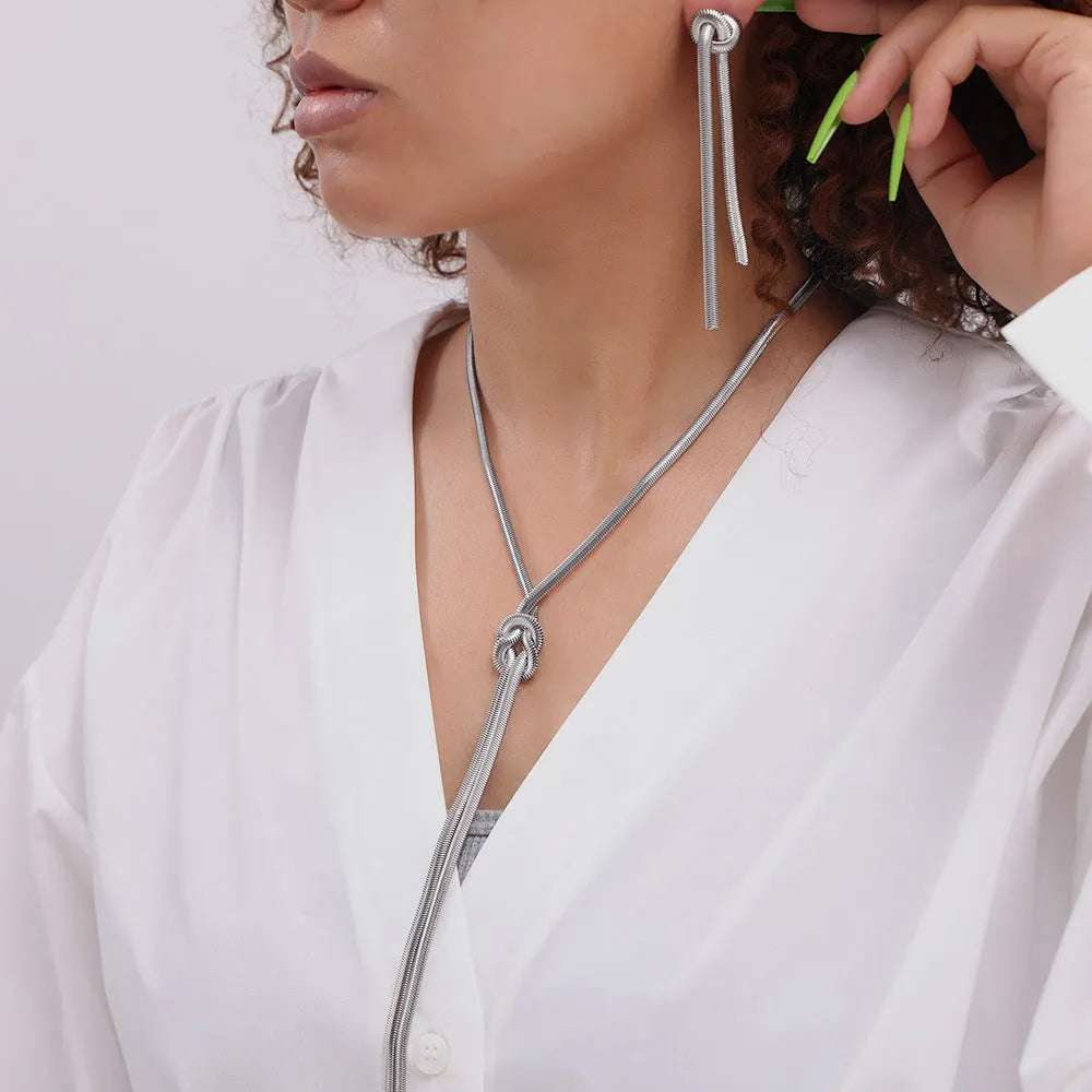 Gold electroplated titanium steel knotted tassel necklace and matching earrings set on a white background.