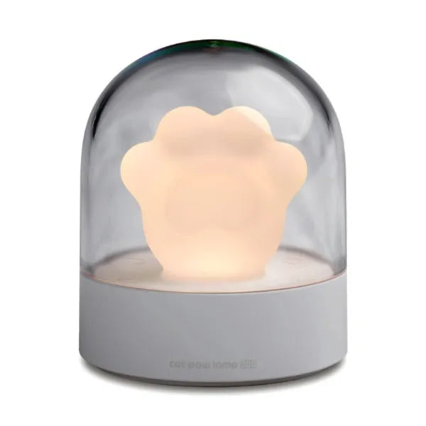 Grey cat paw shaped night light with USB port and button, glowing softly on a wooden desk.