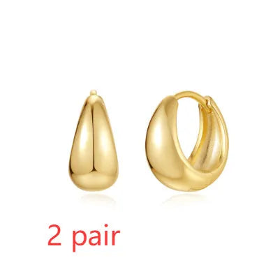 A pair of golden geometric clip-on earrings with a round design element on a white background.