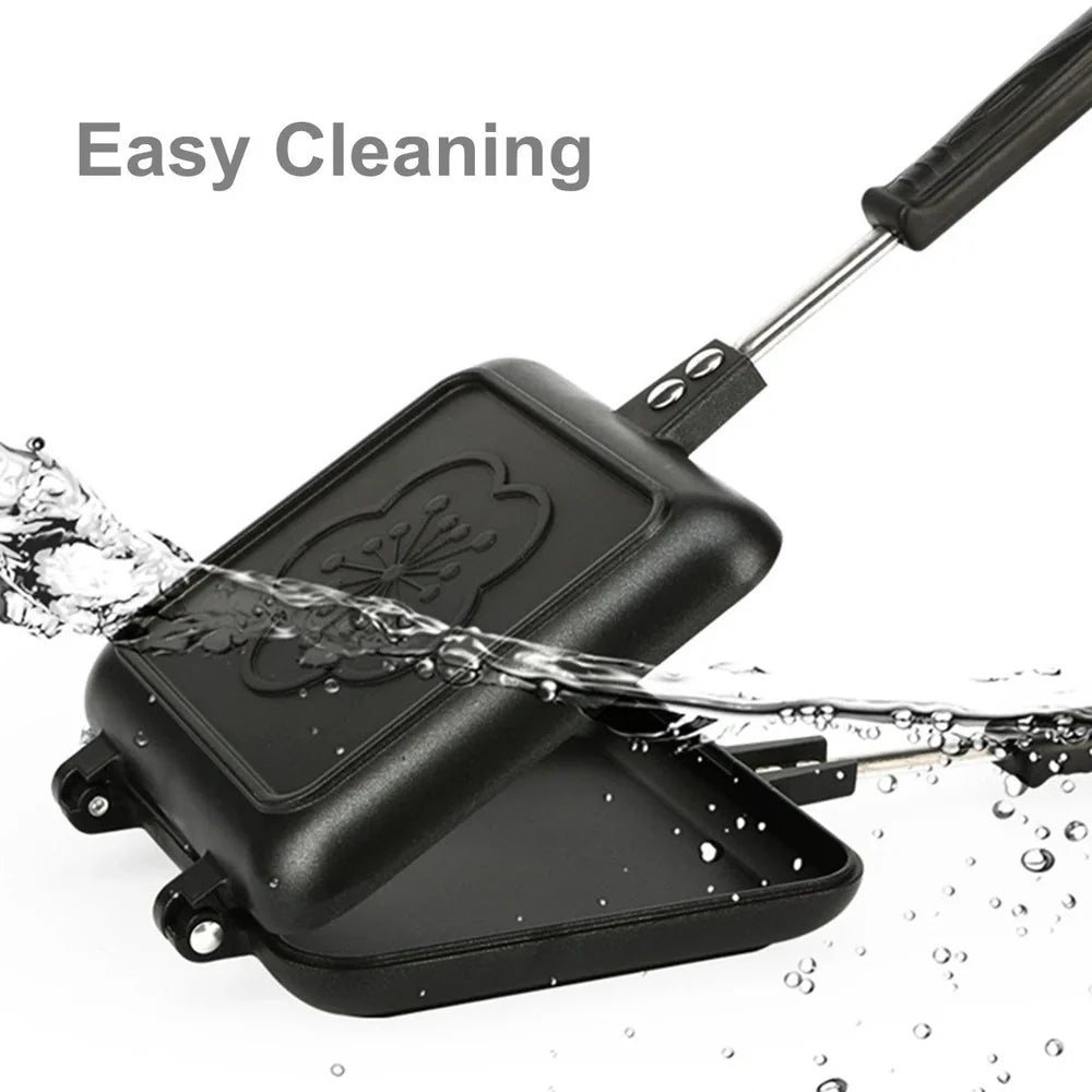 Black double-sided sandwich frying pan with heat-proof handle on stovetop