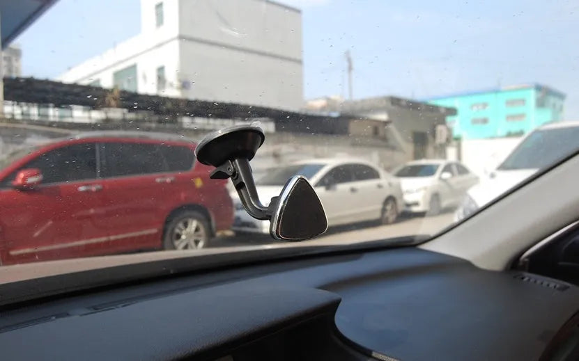 Classic black magnetic car phone holder mounted on a car dashboard, showing a smartphone attached.