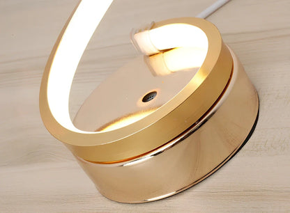 Modern table lamp with curved design, metal base, and acrylic shade offering remote-controlled dimming between warm and white light