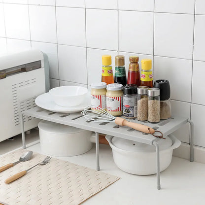 White telescopic kitchen storage rack at adjustable height on a countertop